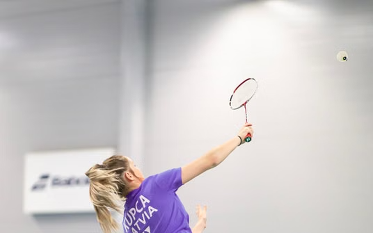 Badminton player lunging to reach a shuttlecock